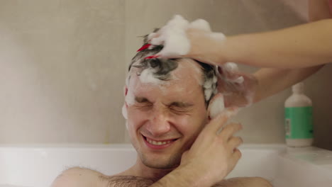 persona lavando el cabello de otra persona en una bañera.