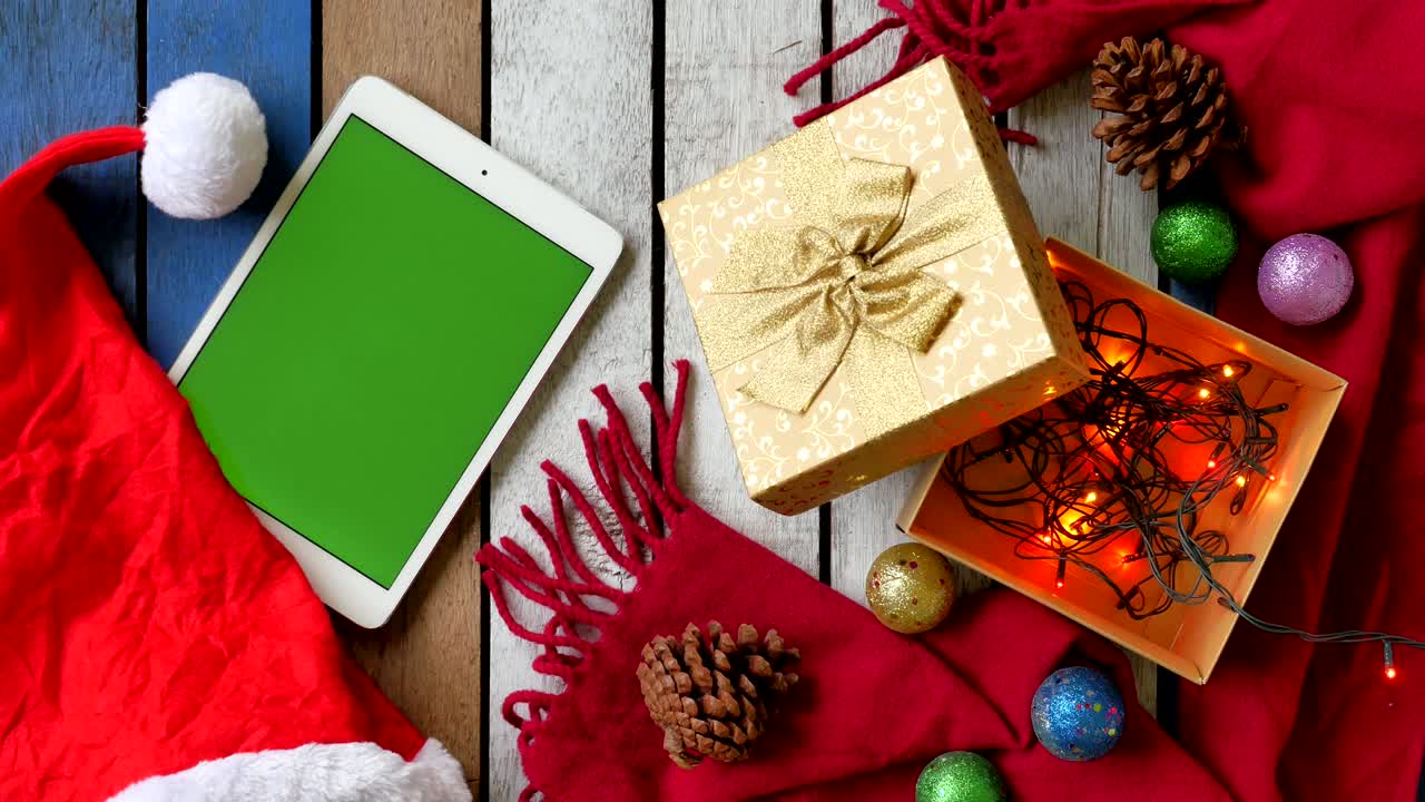 vista superior de la tableta con pantalla verde y decoración de navidad en la mesa de madera.