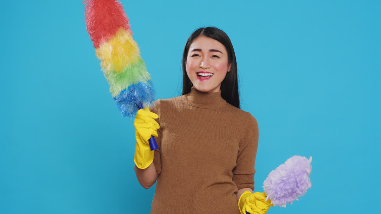 Asian housekeeper looking at professional both feather dusters trying to choose one