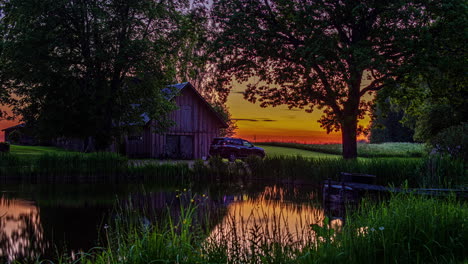 timelapse shot of a wooden cottage with a car parked in front of the cottage beside a lake during during evening time