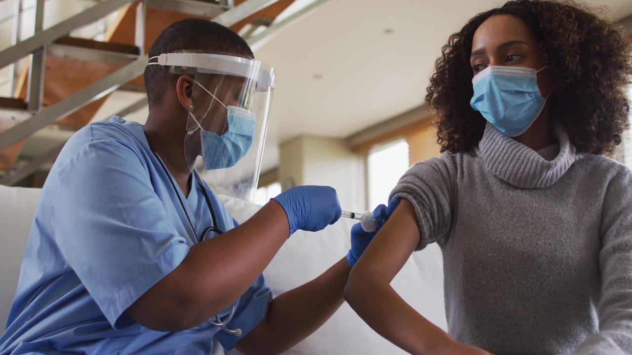 African american female doctor wearing face mask vaccinating african american patient