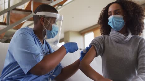 African-american-female-doctor-wearing-face-mask-vaccinating-african-american-patient