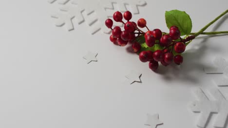 Video-of-christmas-sprig-with-red-berries,-snowflake-patterns-and-copy-space-on-white-background