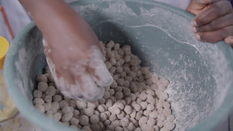 Coating-battered-groundnuts-or-peanuts-in-a-dry-mixture-before-frying---isolated-close-up