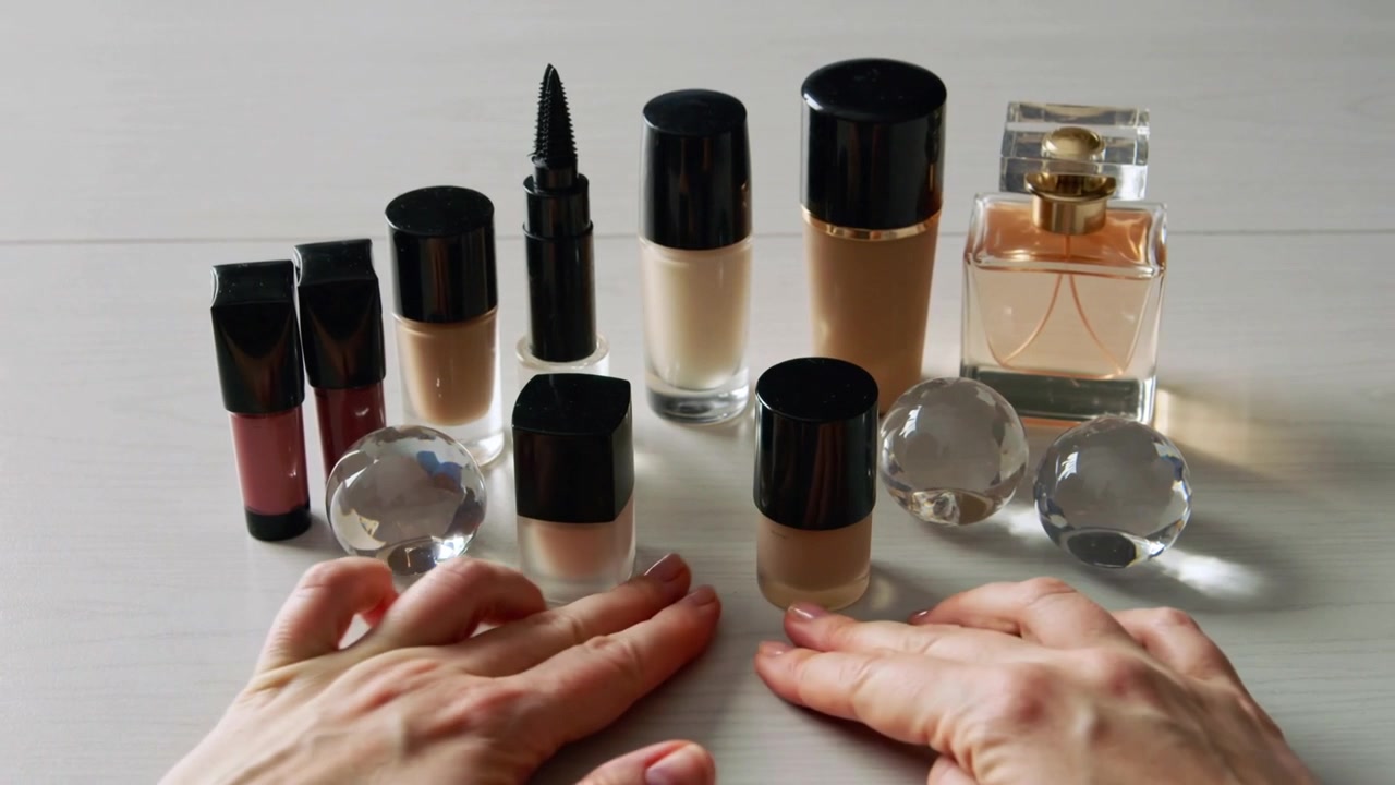 Reaching adult hands adjusting small square-capped bottles on light tabletop, preparing display