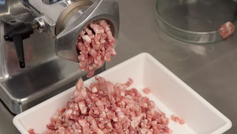 the butcher grinds meat in a coarse-grind machine