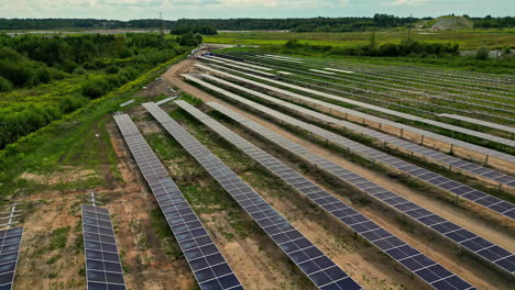 flyover of large solar panel farm with sand, grass, and rows of panels under sunny sky