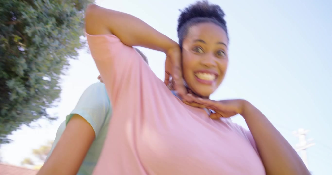 Amigas diversas de costas uma para a outra ao ar livre, com camisetas pastel, mudando de posição e posando para a câmera enquanto ela inclina.