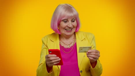 happy senior woman shopping online using credit card and smartphone