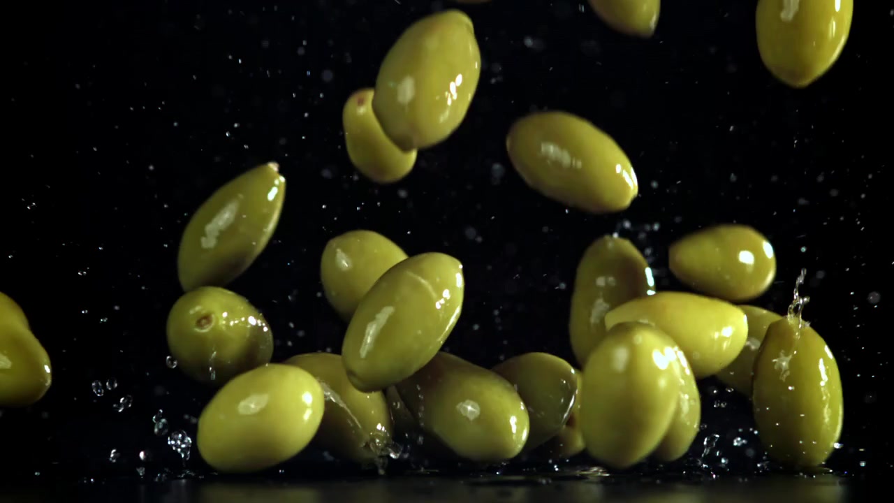 Olive verdi fresche che cadono e schizzano al rallentatore