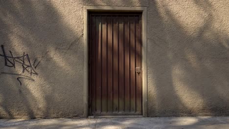 brown metallic door on wall with texture and grafitti at the afternoon, slow dolly in