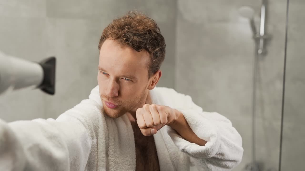 잘생긴 청년은 헤어드라이어로 몸을 불고 자신이 슈퍼맨이라고 상상한다