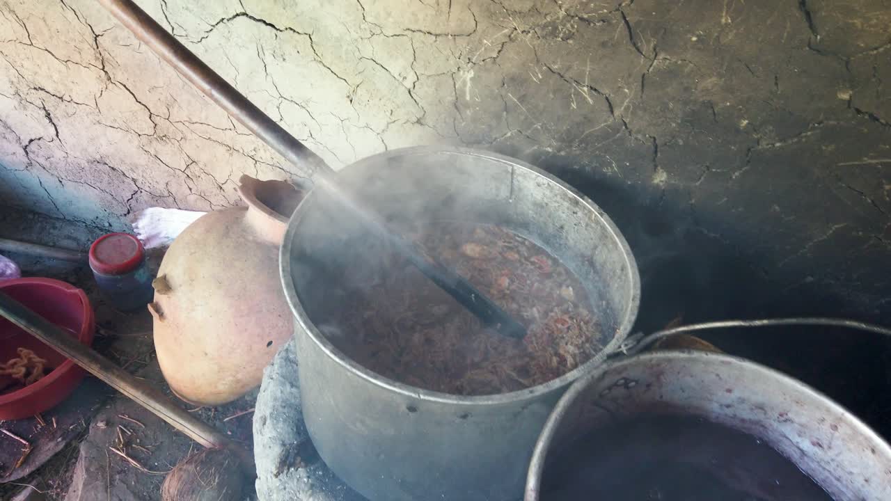 Close-up tangan pengrajin Quechua menempatkan pewarna ungu bubuk yang terbuat dari tanaman lokal kering ke dalam panci air mengepul yang digunakan untuk mewarnai wol alpaka, Lembah Suci, Cusco, Peru