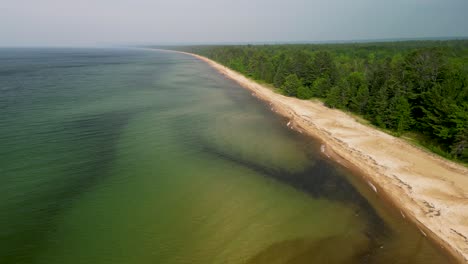 ascenso aéreo de la costa del lago superior con bosque, península superior, michigan