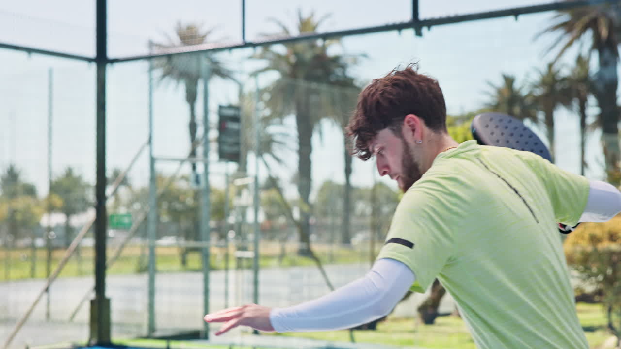 Young Man Serving a Padel Ball on an Outdoor Court