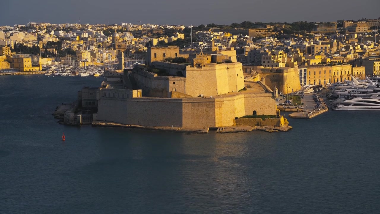 Kultaisen tunnin kallistuskuva Fort St. Angelosta tykkeineen ja tyynine merineen, Malta, 4K.