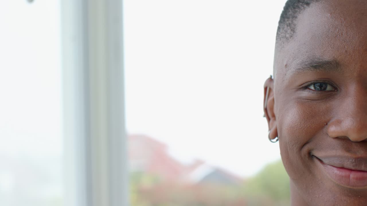 After gaze by window, African American man shifting into smile while engaging camera, copy space