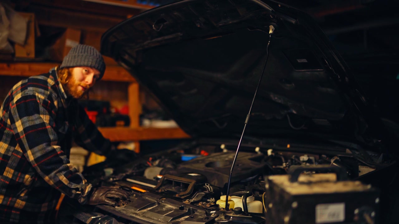 A Mechanic is Explaining the Repair Process While Working Under the Hood of a Car - Medium Shot