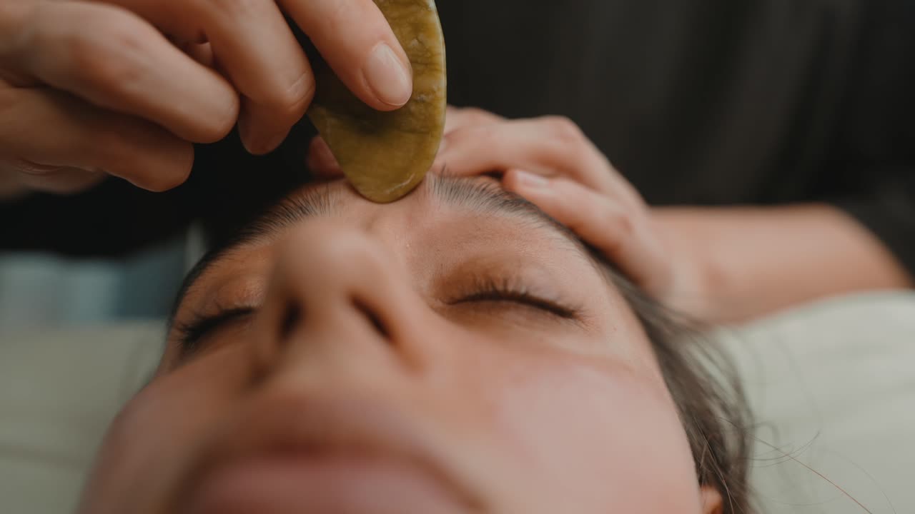 Nærbillede af kvinde, der får Gua Sha ansigtsmassage.
