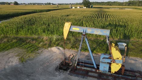 pumpjack pumping oil surrounded with agriculture field, aerial view