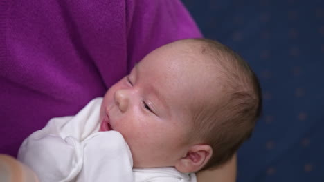 tiny child in mother's hands opens mouth waiting for bottle. mother gives him a bottle and baby takes it hungrily and eats and closes his eyes slowly. close up.
