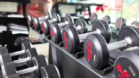 rows of dumbbells in a well-lit gym, emphasizing fitness and strength training. the camera captures the equipment from various angles