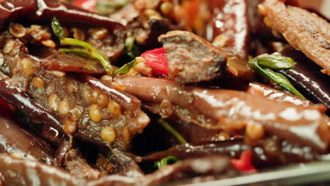close-up of fermented eggplants with red sweet pepper and mustard on plate. preservation of vegetables in glass jars. fermentation preserved aubergine with hot chilli peppers and greens.