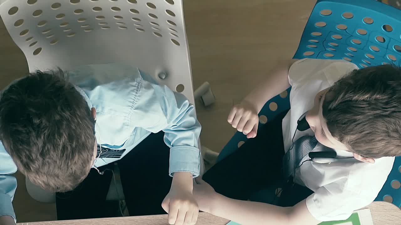 High-angle shot Slow motion Two boys sit on headphones enjoy success in school give each other &amp;quot;five