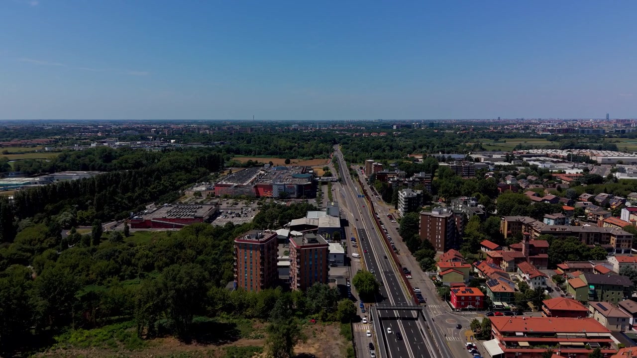 Vista elevada de edifícios comerciais e bairros residenciais em Peschiera Borromeo, perto de Milão, Itália, mostrando desenvolvimento urbano moderno, estradas e infraestrutura suburbana.