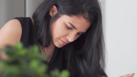 pretty black haired latina woman working on creative project in home office