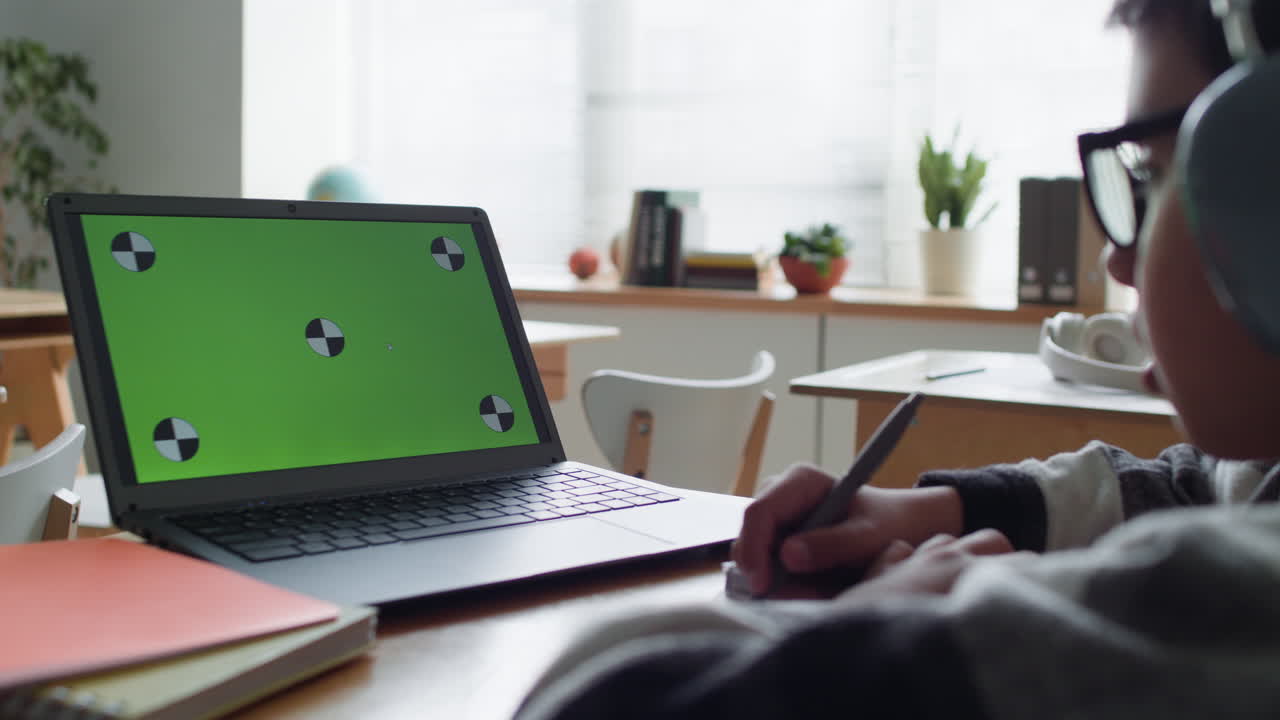 estudiante trabajando en una computadora portátil con pantalla verde