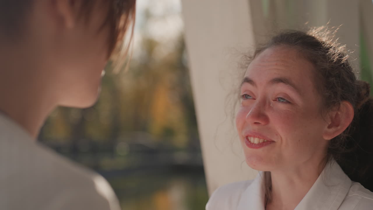 Emotional daughter crying while embraced outdoors, white woman comforted by companion with forehead touch, sunlight through trees, candid park scene, intimate family support and healing