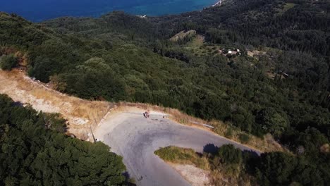 aerial shot of huge bay, lots of trees, winding road and blue sea in corfu, greece