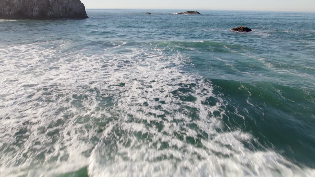 오레곤주 밴든 해변에서 파도 위를 활공하는 4k의 아름다운 공중 드론 샷