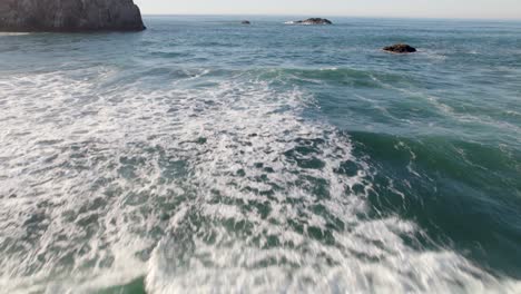 disparo de drones aéreos escénicos de 4k deslizándose sobre las olas en bandon, playa de oregon