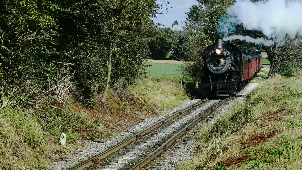 tren de pasajeros de vapor resoplando a lo largo de las tierras agrícolas y el campo amish