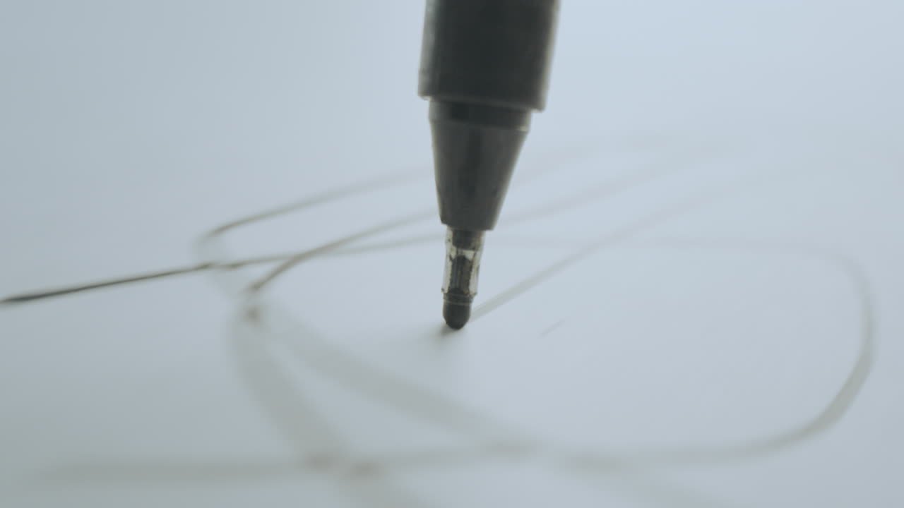 Close-up of a pen drawing lines on paper