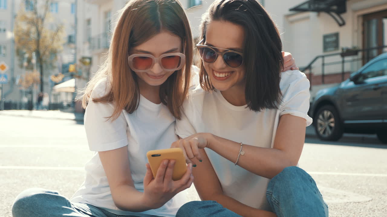 dos amigas mirando un teléfono en la calle