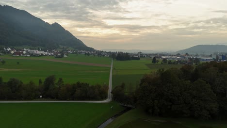 Camino-Rural-Elevado-Aéreo-Entre-Campos-De-Hierba-En-La-Ciudad-De-Bilten-Durante-La-Puesta-De-Sol,-Suiza