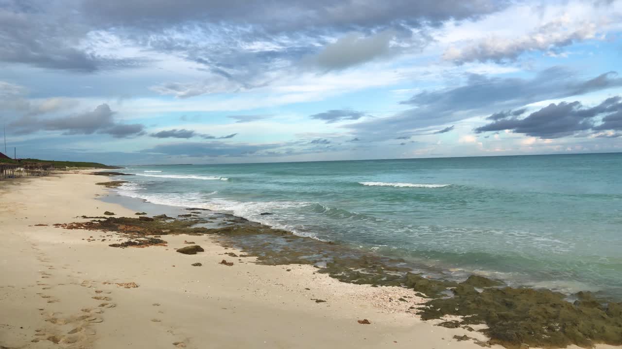 panorámica de la cámara a lo largo de la playa rocosa con formaciones de nubes