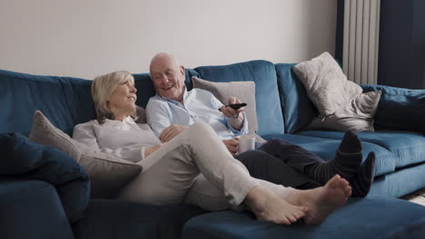 elderly couple relaxing on the couch and watching tv