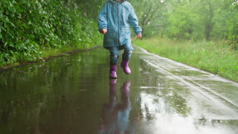 niño animado corre a través del parque lluvioso niño activo salta piscinas de agua de lluvia con deleite desenfrenado