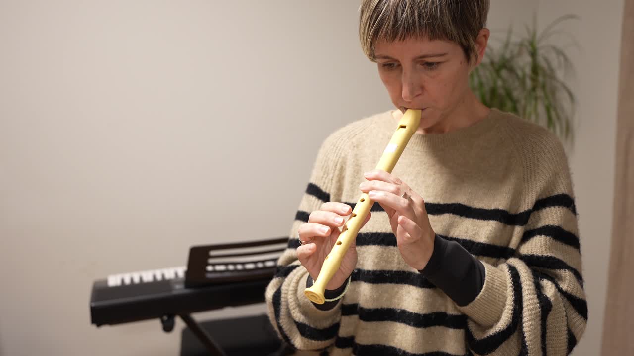 Donna che suona il flauto dolce e legge uno spartito musicale al chiuso