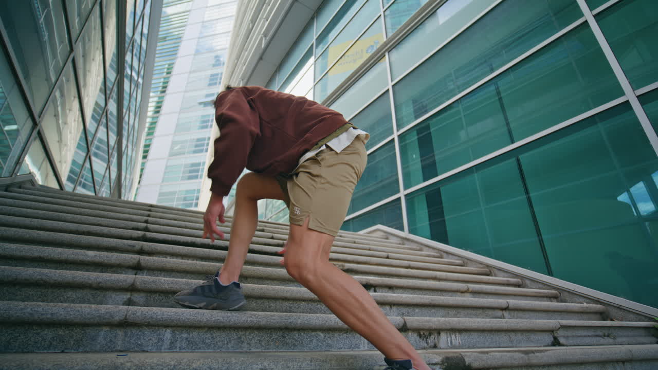 City runner tying sneakers training at modern glass architecture low angle