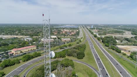 Schließende-Umlaufbahnaufnahme-Eines-Funkturms-Neben-Der-Autobahn-In-Florida-An-Einem-Sonnigen-Tag-Mit-Einem-Adler