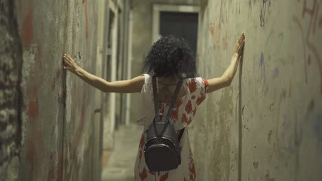 Girl-walking-at-night-on-a-narrow-street-and-touching-the-walls