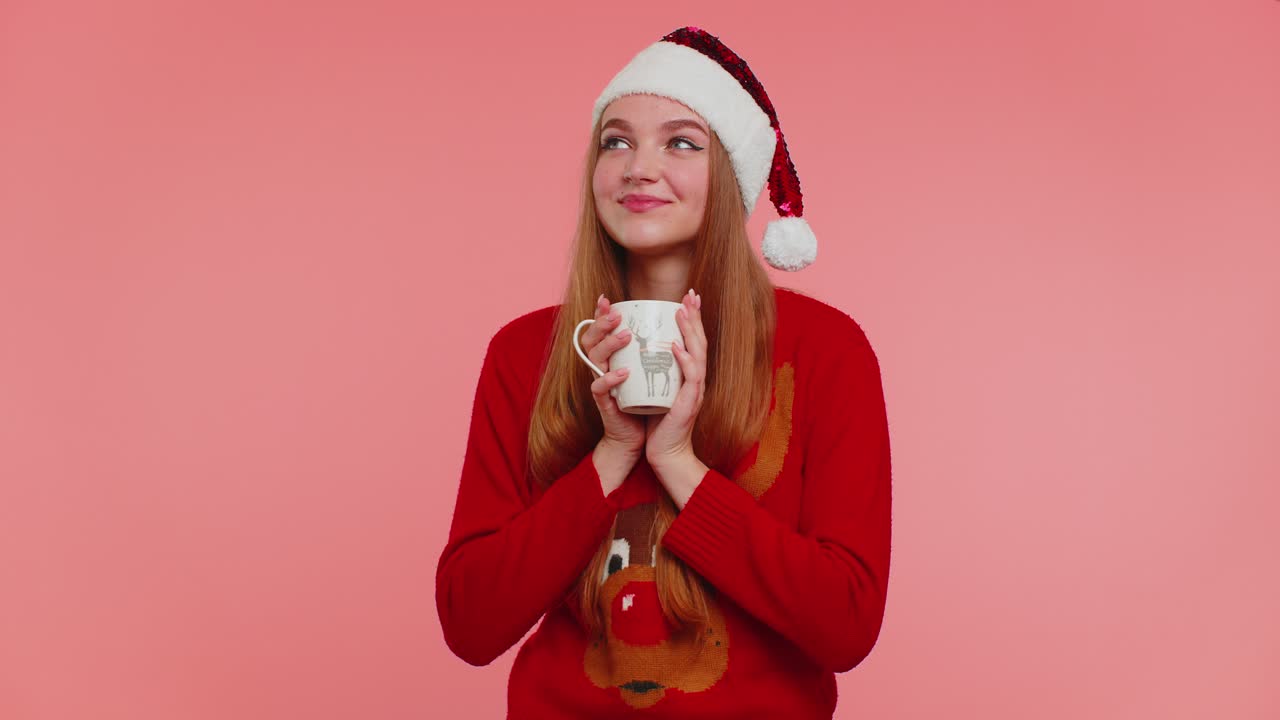 Cheerful girl in christmas santa sweater with hot drink smiling relaxing drinking coffee or tea