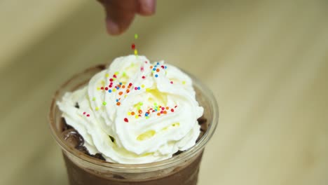 adding sprinkles to whipped cream-topped drinks