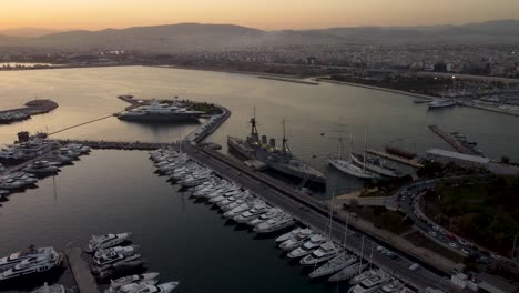 a captivating drone shot of the floisvos marina and averof battleship during a beautiful sunset