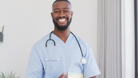 Video-of-happy-african-american-male-doctor-looking-at-camera